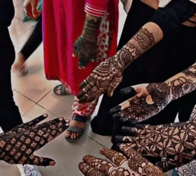 A group of students proudly showcasing their beautiful henna (mehndi) designs on their hands.