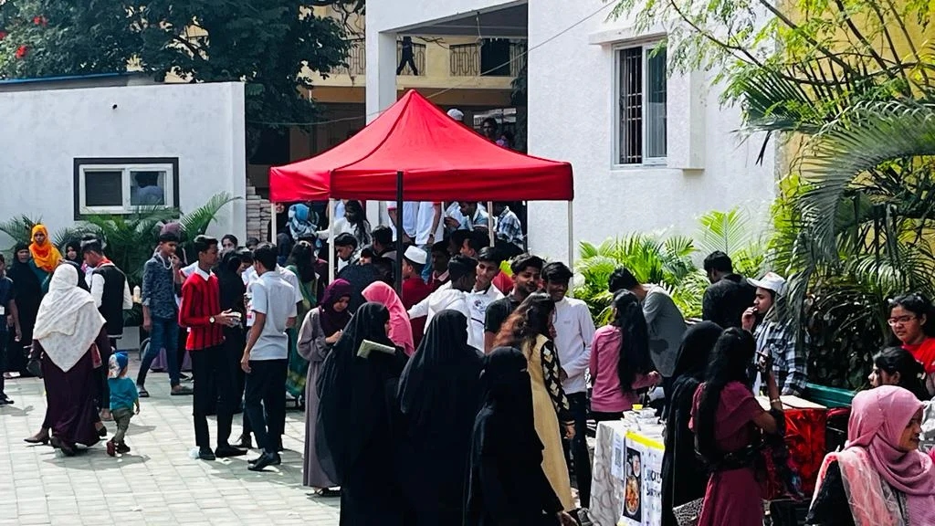 A crowded courtyard scene with a red canopy tent and many students mingling at the food fest.