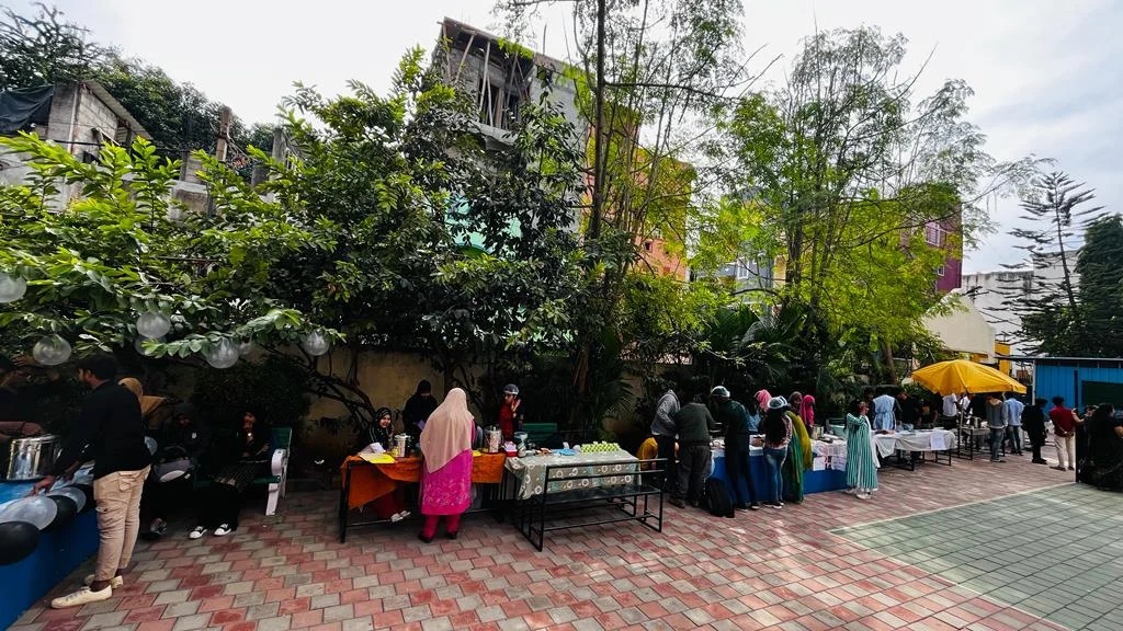 An outdoor food fest setup with stalls and students queuing up under trees.