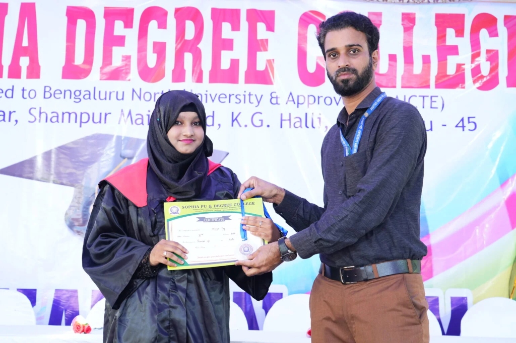 A female graduating student receiving a certificate from a staff member.