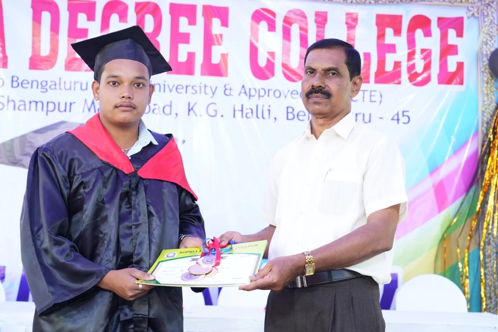 A male graduating student in a cap and gown receiving his certificate.