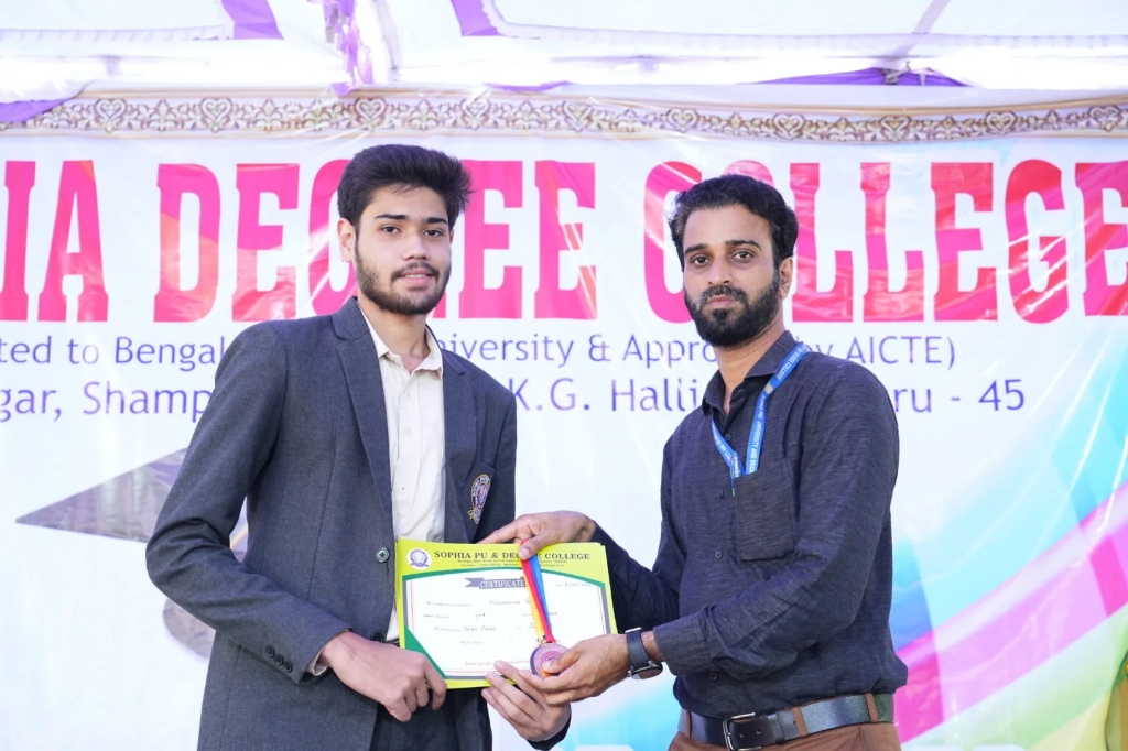 A male graduate receiving a certificate and medal from a faculty member.