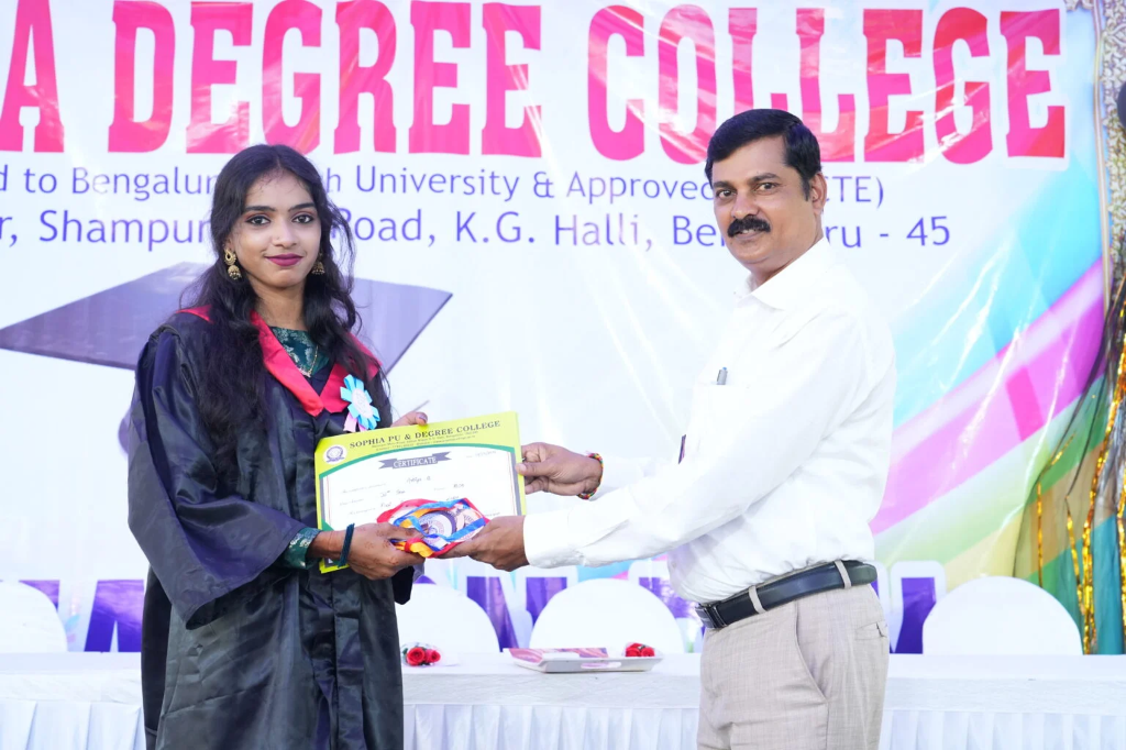 A female graduating student receiving her certificate from a staff member.