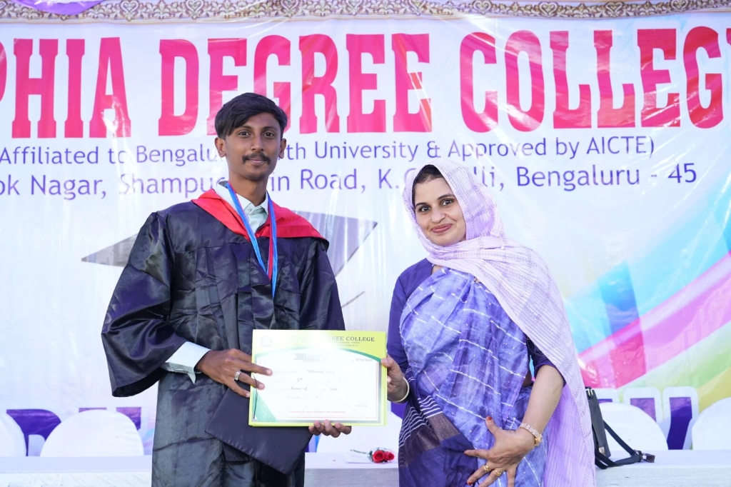A male graduating student receiving his certificate from a female staff member.