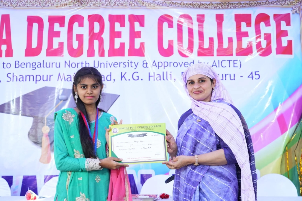 A female graduating student receiving her certificate from a female staff member.