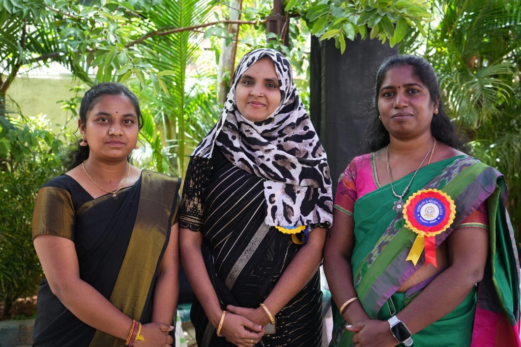 Three female faculty and staff members smiling together at the graduation event.