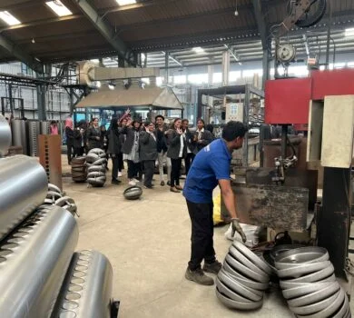 Students exploring a manufacturing plant, observing industrial machinery.