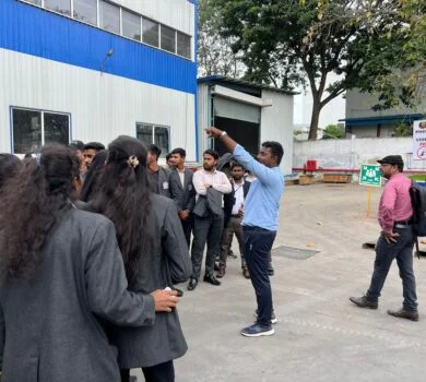 A factory representative explaining the manufacturing process to students inside the plant.