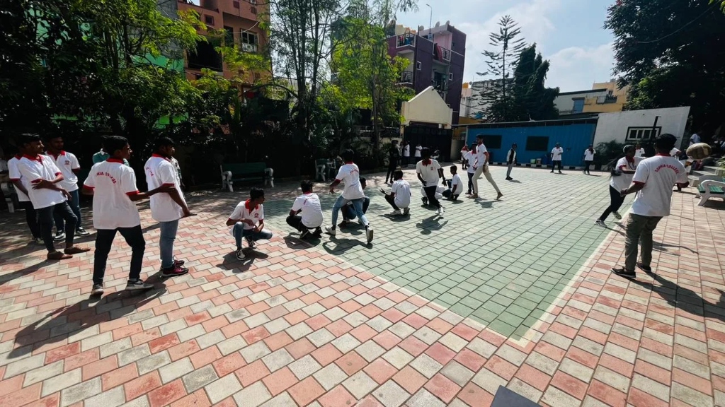 Students in white shirts actively playing a game on the college sports court.